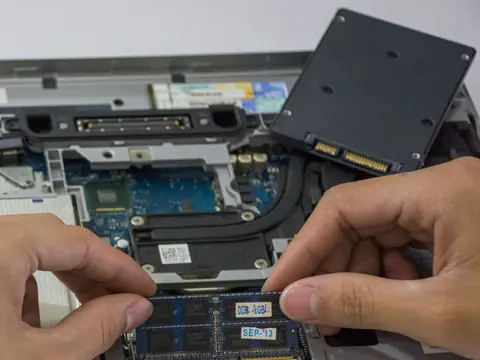 Foto ilustrativa: SSD e pente de memória num notebook aberto